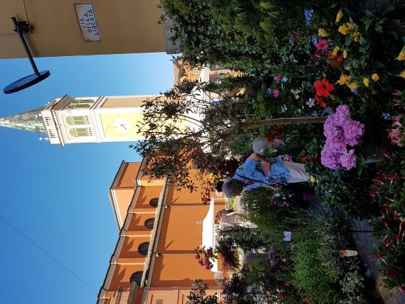 Bancarella con fiori e sullo sfondo campanile