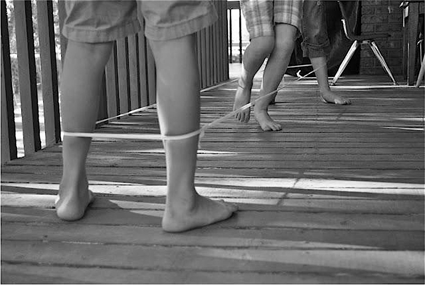 <tre bambini che giocano con un elastico alle caviglie