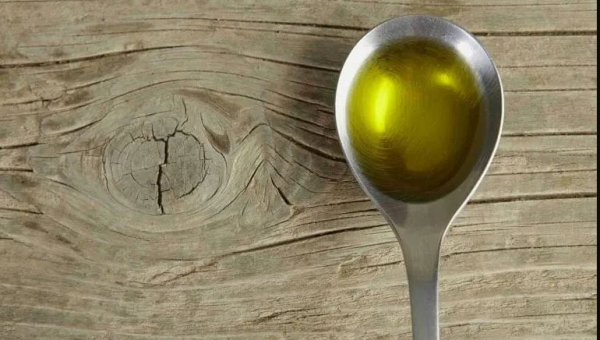 cucchiaino contente olio su un tavolo di legno 