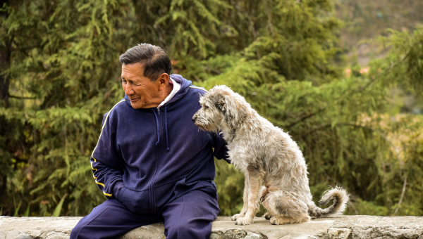 Anziano seduto su muricciolo con il suo fedele cane